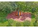Aerial view of the community playground surrounded by mulch, green grass and some flowering trees at 9405 Ashley Dr, Weeki Wachee, FL 34613