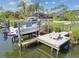 Waterfront home featuring a private boat dock, boat lift, and backyard lawn with lush landscaping at 944 Symphony Isles Blvd, Apollo Beach, FL 33572