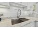 Close up of a kitchen sink, faucet, marble countertop, white shiplap backsplash, and under cabinet lighting at 944 Symphony Isles Blvd, Apollo Beach, FL 33572
