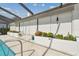 Home's screened-in pool area with white hurricane shutters and lovely garden at 944 Symphony Isles Blvd, Apollo Beach, FL 33572