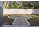 Backyard showcasing stone fire pit, white vinyl fence, and mature trees at 1545 Pasadena Dr, Dunedin, FL 34698