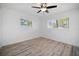 Bright bedroom featuring wood-look flooring, two windows with natural light, and a ceiling fan at 1545 Pasadena Dr, Dunedin, FL 34698