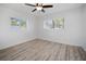 Bright bedroom featuring wood-look flooring, two windows with natural light, and a ceiling fan at 1545 Pasadena Dr, Dunedin, FL 34698