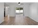 Bright living room with light wood flooring, ceiling fan, and sliding glass door leading to outdoor patio at 1545 Pasadena Dr, Dunedin, FL 34698