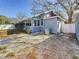 View of the home's gray exterior, side windows, AC unit, white fencing, and gravel ground cover at 2111 26Th S St, St Petersburg, FL 33712