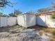 An outdoor metal shed sits on the gravel ground cover behind a white fence at 2111 26Th S St, St Petersburg, FL 33712