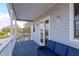 Comfortable covered balcony with blue deck, white railing, blue wicker furniture, and waterway views at 320 Georgia Ave, Crystal Beach, FL 34681