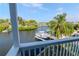 Picturesque balcony view of waterfront canal, docked boat, and lush tropical landscape with palm trees at 320 Georgia Ave, Crystal Beach, FL 34681