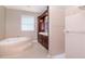 Bright bathroom featuring a soaking tub with tile surround, tile floors and wood cabinets with double sinks at 320 Georgia Ave, Crystal Beach, FL 34681