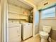 Small bathroom with toilet, window, shelves, and laundry appliances at 3902 W Iowa Ave, Tampa, FL 33616