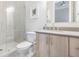 Bathroom featuring a glass enclosed shower with vertical tiles, a toilet, and a vanity with natural wood cabinets at 619 Danube Ave, Tampa, FL 33606