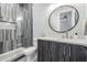 Bathroom with a glass enclosed shower, vanity with gray cabinets, and a large circular mirror at 619 Danube Ave, Tampa, FL 33606