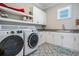 Well-lit laundry room featuring patterned tile floors, white cabinets, and modern washer and dryer units at 619 Danube Ave, Tampa, FL 33606