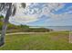 Scenic waterfront view with a walkway leading to the water, surrounded by green grass and tropical vegetation under a blue sky at 6365 Bahia Del Mar Blvd # 112, St Petersburg, FL 33715