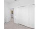 Bedroom featuring closet doors, neutral walls, and tile flooring, with a glimpse into the adjoining bathroom at 8069 Shore Lake Dr, Englewood, FL 34224