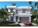 Modern home featuring clean lines, large windows, and a gray garage door, complemented by lush landscaping at 902 W Fribley St, Tampa, FL 33603