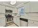 Bright kitchen featuring modern stainless steel appliances, white cabinetry, and sleek countertops at 9111 Sterling Ln, Port Richey, FL 34668