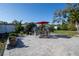 Paved patio features a dining set, red umbrella, and landscaped greenery under a clear blue sky at 1091 Mcfarland St, Dunedin, FL 34698