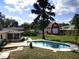 Inviting backyard with a sparkling pool, well-maintained lawn, and a charming red outbuilding at 1101 King Arthur Ct, Valrico, FL 33594