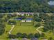 Aerial view of the community with tennis courts, green space, walking trails, and trees at 12333 Woodlands Cir, Dade City, FL 33525