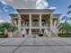 Exterior of a beige community clubhouse featuring stately columns, staircases, and a wide-open patio at 12333 Woodlands Cir, Dade City, FL 33525