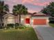 Charming single-story home featuring a red tile roof, an attached two-car garage, and lush tropical landscaping at 12333 Woodlands Cir, Dade City, FL 33525