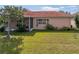 A peach colored house with a red tile roof, an arched window, a screened lanai, and a manicured lawn at 12333 Woodlands Cir, Dade City, FL 33525