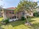 Exterior view shows manicured lawn and screened in patio in a peach hued home with red tile roof at 12333 Woodlands Cir, Dade City, FL 33525