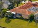 Aerial of a peach house with a red tile roof and covered lanai, surrounded by lush green lawn at 12333 Woodlands Cir, Dade City, FL 33525