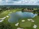 Picturesque aerial view of the golf course with a serene lake and lush green fairways at 12333 Woodlands Cir, Dade City, FL 33525