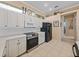 Bright kitchen featuring white cabinets, stainless steel oven, microwave, and a black refrigerator at 12333 Woodlands Cir, Dade City, FL 33525