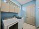 Blue laundry room with washer and dryer, cabinets, sink, and tiled floor at 12333 Woodlands Cir, Dade City, FL 33525