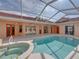 Covered, in-ground pool and hot tub with peach colored tile, and view of the home at 12333 Woodlands Cir, Dade City, FL 33525