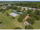 Aerial view of a vibrant recreational area featuring tennis courts, a playground, and open green spaces at 12333 Woodlands Cir, Dade City, FL 33525