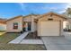 Tan single-story home featuring a one car garage, black door, and a small garden under the window at 1242 Holly Cir, Oldsmar, FL 34677