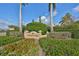 Community entrance sign surrounded by colorful flowers, lush greenery, and swaying palms at 1401 Ventana Dr, Sun City Center, FL 33573