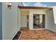 Brick paved courtyard featuring a glass sliding door entry and a white front door entry with exterior lighting at 14810 Feather Cove Ln, Clearwater, FL 33762