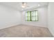 Spacious bedroom with neutral carpet, ceiling fan, and window with light green curtains at 17596 Terrazzo Way, Land O Lakes, FL 34638