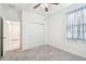 Bright bedroom featuring neutral carpet, ceiling fan, closet, and a window with blue patterned curtain at 17596 Terrazzo Way, Land O Lakes, FL 34638