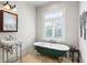 Elegant bathroom boasts a classic clawfoot tub and stylish sink with window views at 2028 Illinois Ne Ave, St Petersburg, FL 33703