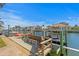 View of a boat dock on the water with a bench, boat lift, jet ski and waterfront homes in the background at 2028 Illinois Ne Ave, St Petersburg, FL 33703