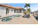 Exterior home view featuring a pool, spa, travertine tile patio, summer kitchen, and outdoor seating near the waterfront at 2028 Illinois Ne Ave, St Petersburg, FL 33703