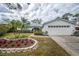 Charming home featuring a two-car garage, blue shutters, and a meticulously landscaped front yard with beautiful flowerbeds at 2086 Whitney N Pl, Clearwater, FL 33760