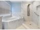 Bright bathroom featuring a modern shower system and a luxurious soaking tub with marble tiling at 212 Arbor Woods Cir, Oldsmar, FL 34677