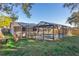 An outdoor view of a pool that is enclosed by screens and features a table and fire pit nearby at 2195 Glen Dr, Safety Harbor, FL 34695