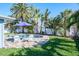 Lush backyard featuring a pool, patio with white chairs, vibrant lawn, and mature trees at 230 Julia S Cir, St Pete Beach, FL 33706