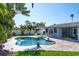 Backyard with a freeform pool, patio area, lush landscaping, and seating under an umbrella at 230 S Julia Cir, St Pete Beach, FL 33706