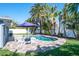 Inviting backyard pool area with beautiful landscaping and lounge chairs with a shade umbrella at 230 S Julia Cir, St Pete Beach, FL 33706