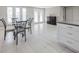 Bright dining area featuring tile flooring, glass table, and adjacent kitchen with white cabinets and granite counters at 3939 Rudder Way, New Port Richey, FL 34652