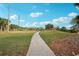 Scenic paved walking path extending into a green space with palms and blue skies at 4307 Woodmans Chart # 132, Sarasota, FL 34235